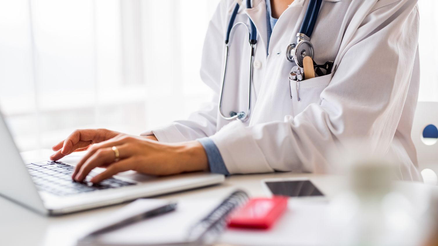 healthcare professional typing on laptop